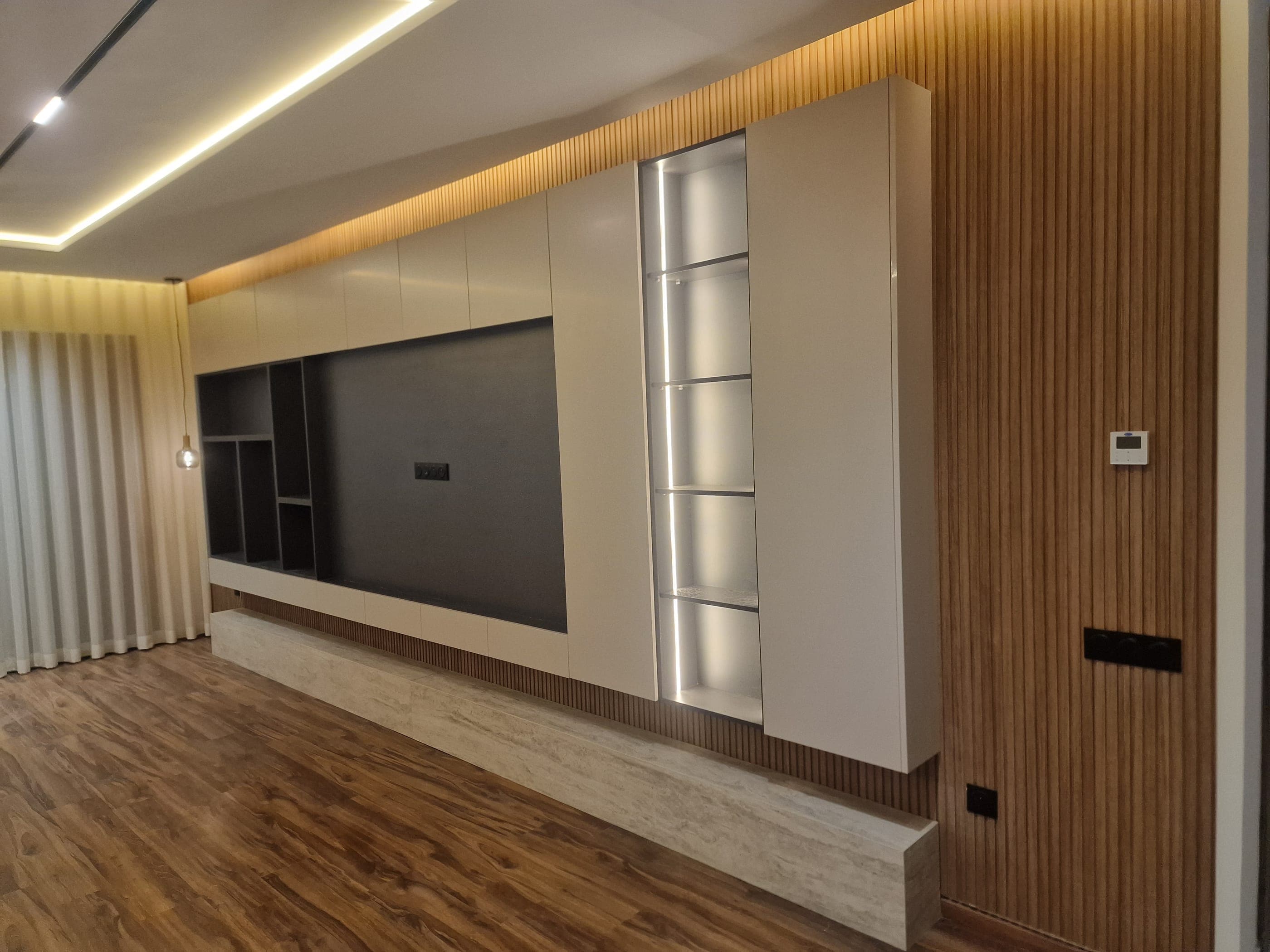 Séjour avec meuble TV, bibliothèque et habillage mural en lames de bois sur mesure