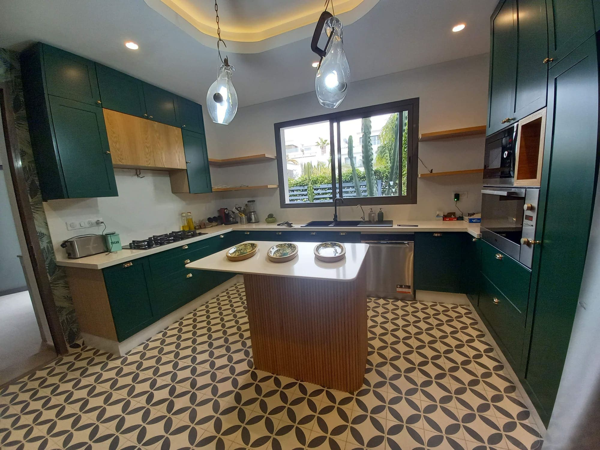 Cuisine verte en U avec îlot habillé de lames de bois et carrelage à motifs