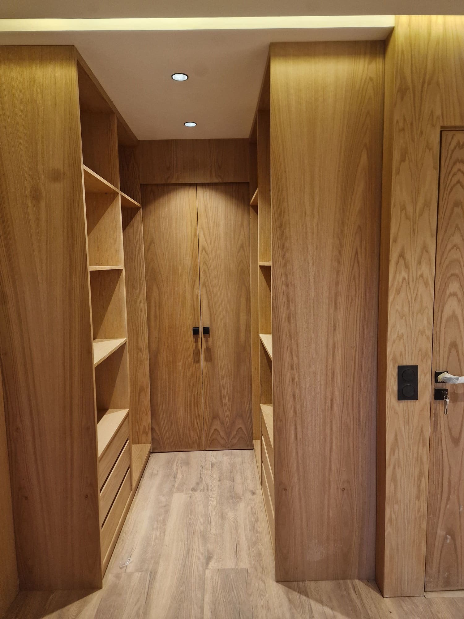Dressing en bois clair avec colonnes de rangement, tiroirs et porte assortie