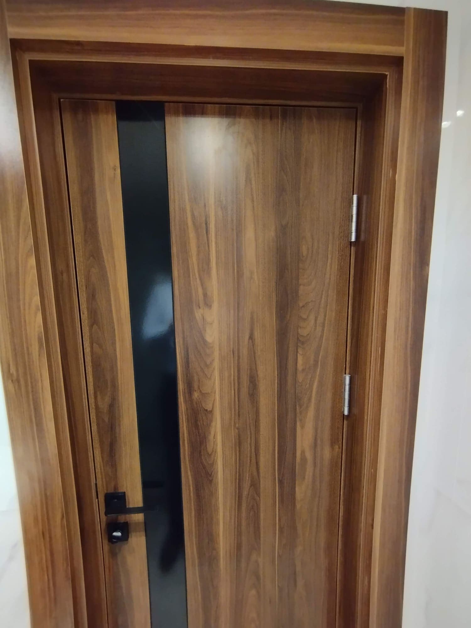 Porte intérieure en bois foncé avec bande vitrée noire et poignée noire